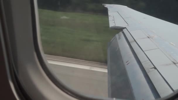 A plane with a flap lowered on the wing lands on the runway, slows down — Stock Video