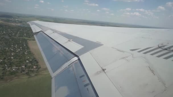 Wing aircraft is tilted, gaining height. Below houses, fields on the background — Stock Video