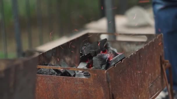 Een close-up. Hand ventilator een vuur met een schop in een barbecue grill — Stockvideo