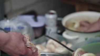 Erkekler, ülkedeki tencere ve turna tüneğinden şişlere et bağlıyor.