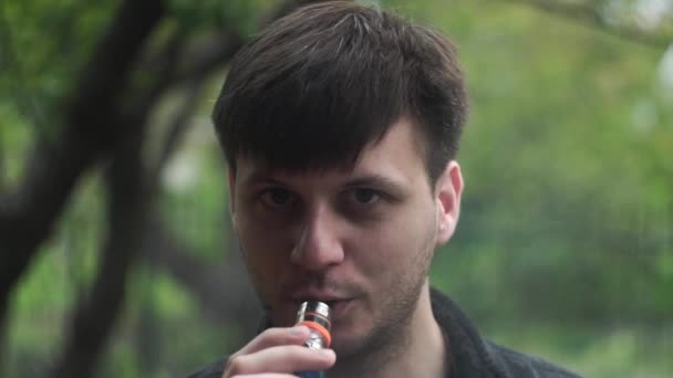 Chlápek vydechne bílý kouř z elektronické cigarety do kamery — Stock video