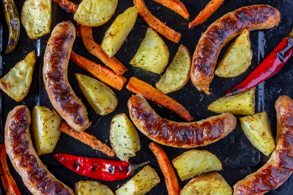 Grilled sausages with potatoes, carrots and chilli. German cuisine. — Stock Photo, Image