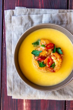 Ahşap arka planda ızgara karidesli krem peynir çorbası.