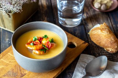 Ahşap arka planda ızgara karidesli krem peynir çorbası.