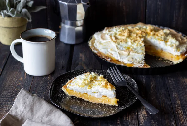 Lemon pie with meringue on a wooden background.