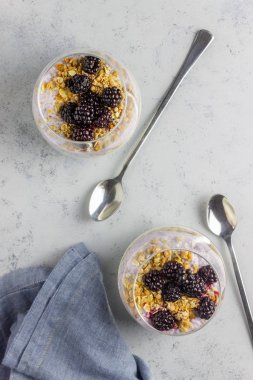 Gri arka planda yoğurt, chia tohumu ve böğürtlen. Kahvaltıda. Sağlıklı beslenme.