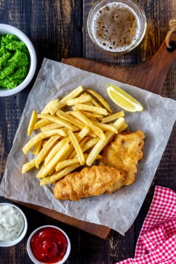 Ahşap zeminde balık ve patates kızartması. İngiliz fast food. Yemek tarifleri. Atıştırmalıktan biraya. İngiliz mutfağı.