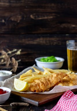 Ahşap zeminde balık ve patates kızartması. İngiliz fast food. Yemek tarifleri. Atıştırmalıktan biraya. İngiliz mutfağı.