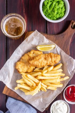 Ahşap zeminde balık ve patates kızartması. İngiliz fast food. Yemek tarifleri. Atıştırmalıktan biraya. İngiliz mutfağı.