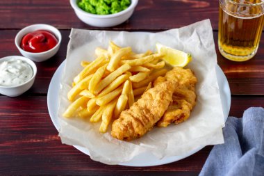 Ahşap zeminde balık ve patates kızartması. İngiliz fast food. Yemek tarifleri. Atıştırmalıktan biraya. İngiliz mutfağı.
