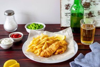 Ahşap zeminde balık ve patates kızartması. İngiliz fast food. Yemek tarifleri. Atıştırmalıktan biraya. İngiliz mutfağı.