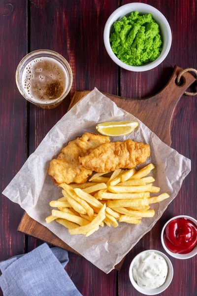 Ryby a hranolky na dřevěném pozadí. Britské fast food. Recepty. Svačinka na pivo. Anglická kuchyně. — Stock fotografie