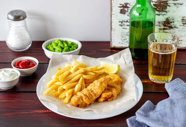 木の背景に魚やチップ。イギリスのファーストフード。レシピだビールを飲みなさい。英語料理. — ストック写真