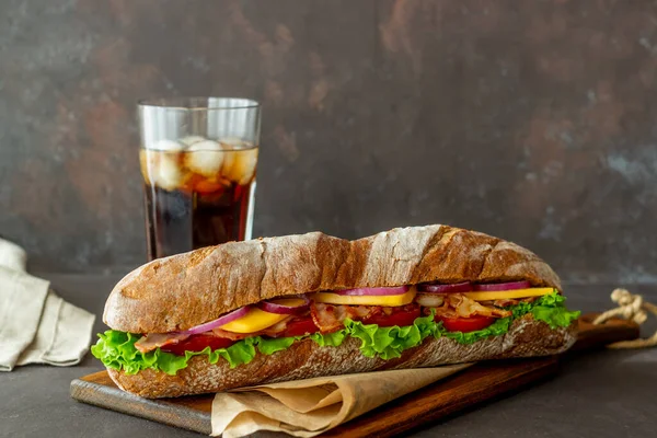 Un sándwich de pan negro con ensalada, tocino, tomate, queso y cebolla. El desayuno. Comida rápida . — Foto de Stock