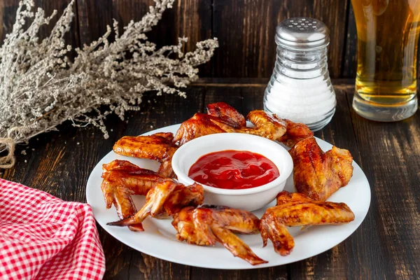 Grilled chicken wings with beer and red sauce on a wooden background. Snack to beer. Barbecue. Recipes.