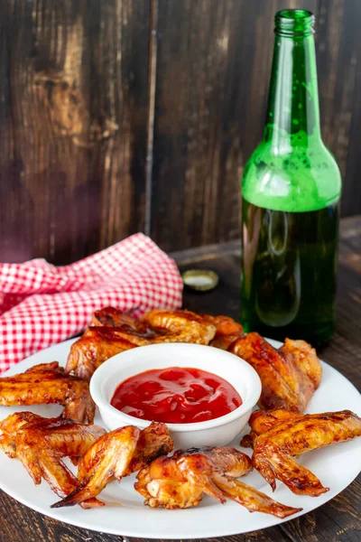 Grilled chicken wings with beer and red sauce on a wooden background. Snack to beer. Barbecue. Recipes.