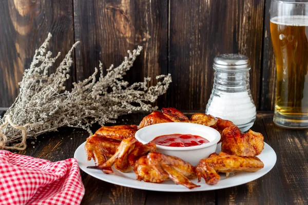 Grilled chicken wings with beer and red sauce on a wooden background. Snack to beer. Barbecue. Recipes.