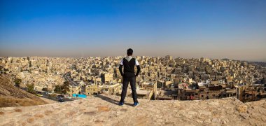 Amman, Jordan. Kasım 2019 civarı. Hintli bir erkek turist Amman şehrinin panoramik manzarasına şaşkınlıkla bakar..