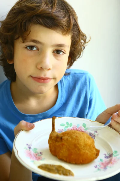 Мальчик держит в руках тарелку курицы — стоковое фото