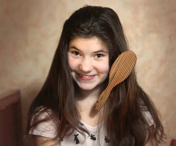 Menina adolescente tentar pentear seu longo cabelo grosso escuro — Fotografia de Stock