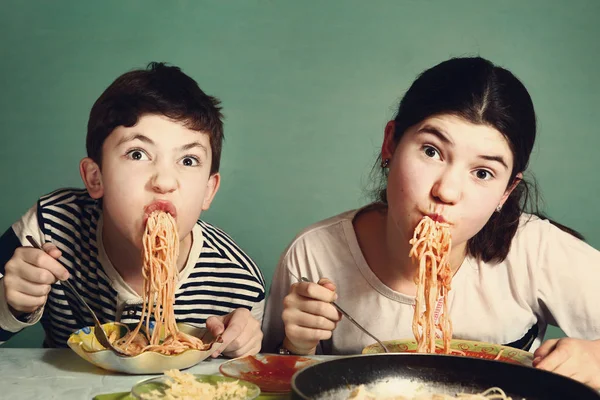 Feliz adolescente irmãos menino e menina comer espaguete — Fotografia de Stock