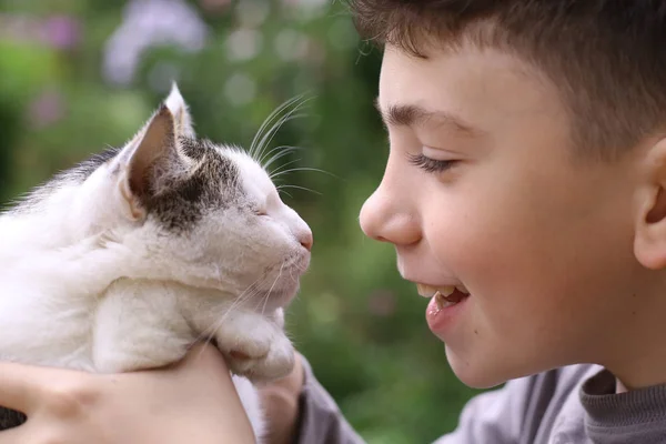 Счастливый мальчик держит кота улыбающегося крупным планом фото — стоковое фото