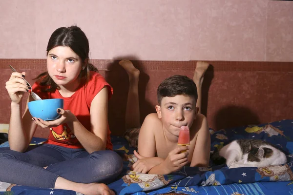 Dospívající sourozenci bratr a sestra ležel v posteli s kočkou — Stock fotografie