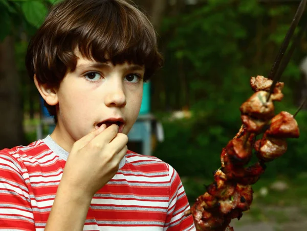 Adolescent garçon avec viande de bœuf rôtie shashlik sur broche en fer braiser — Photo