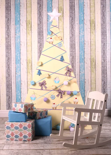 Interiér vánoční výzdoby se stromovým prezentacím a dětskou houpací židlí — Stock fotografie