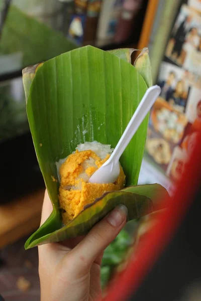 Kleefrijst met mango puree in palm blad straat fastfood dessert in handen van het kind — Stockfoto