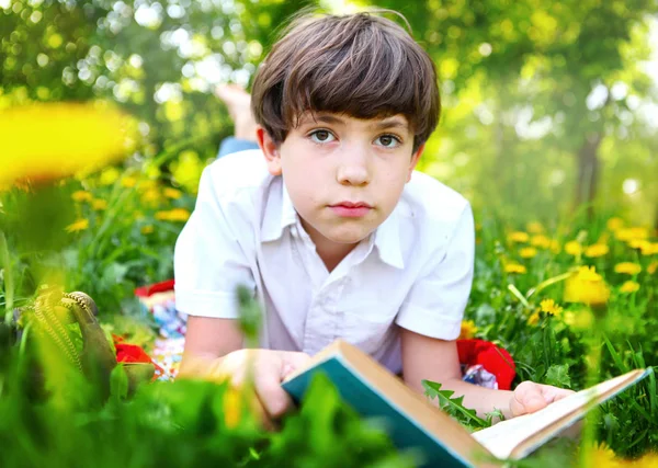 Genç çocuk açık havada kitap okuyor. — Stok fotoğraf