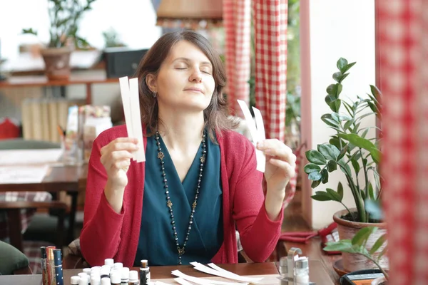 young woman in cafe with tea set smell perfumes with blotter close up photo