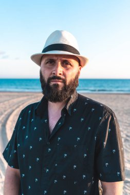 Sakallı ve plajda beyaz şapkalı bir adamın portresi.