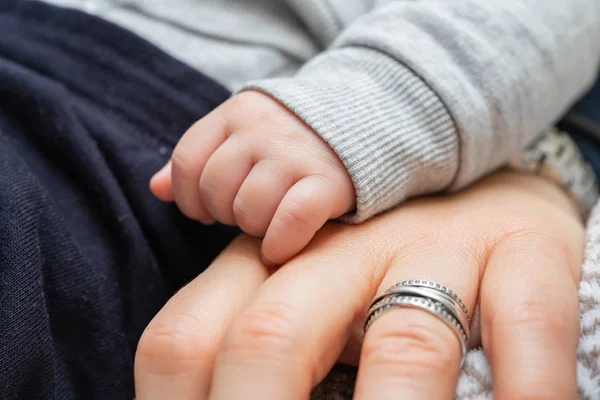 A baby\'s hand on top of his mother\'s hand