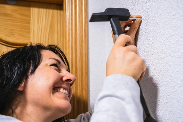 A woman hammering a nail into a wall