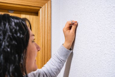 Çekiçle çakmadan önce elinde çivi tutan bir kadın.