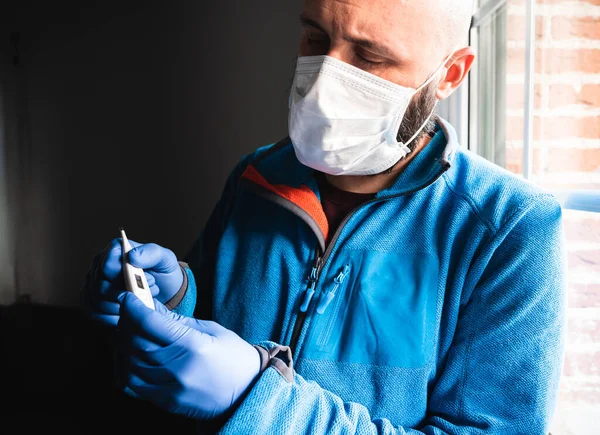 Άρρωστος Άνθρωπος Μάσκα Και Ιατρικά Γάντια Που Ελέγχει Ένα Θερμόμετρο — Φωτογραφία Αρχείου