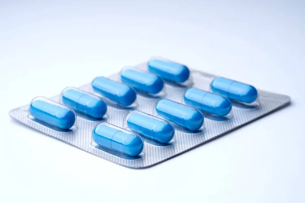 Closeup of blue pills in packaging on a white background with texture