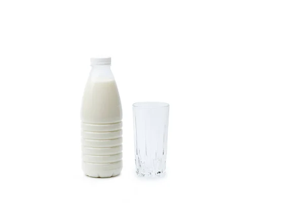 乳の完全なプラスチックボトルと白い背景に隔離された空のガラス — ストック写真