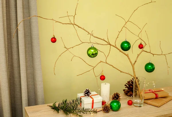Kerstversiering. Groene ballen, tak van boom, geschenkdozen, kaars, dennenappels, Diy idee voor interieur. — Stockfoto