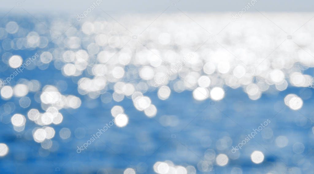 Sea in the sunlight. Blurred calm blue water bokeh background