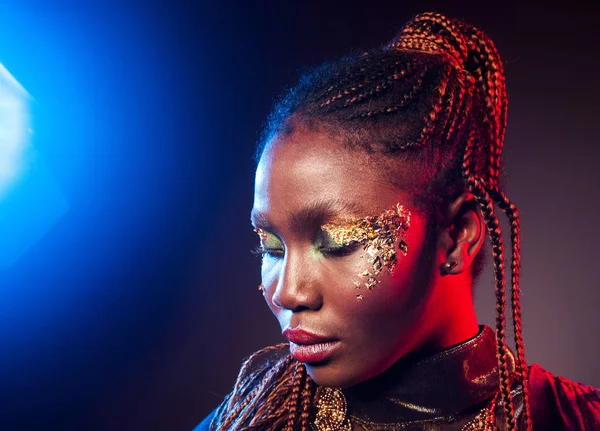 Молодая африканская женщина с африканской прической и золотым блестящим макияжем. Студийный снимок Классический синий цвет 2020 года — стоковое фото