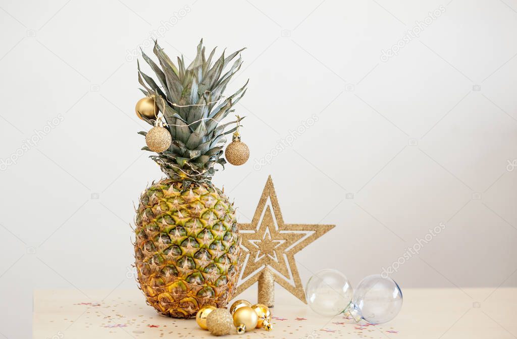 Pineapple decorated wih Christmas golden balls on white background, holiday Christmas concept of decor