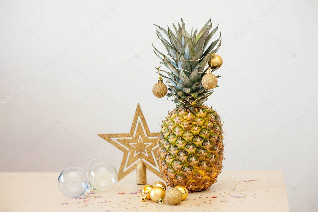 Pineapple decorated wih Christmas golden balls on white background, holiday Christmas concept of decor