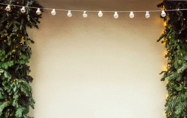 Parede com grinalda de lâmpadas, pinheiros de Natal e luzes e decorações, fundo festivo de inverno — Fotografia de Stock
