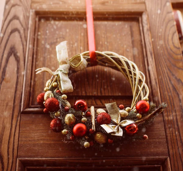 Ghirlanda di Natale appesa fuori sulla porta in inverno fatta di rami d'albero, decorazioni, palle e nastri — Foto Stock