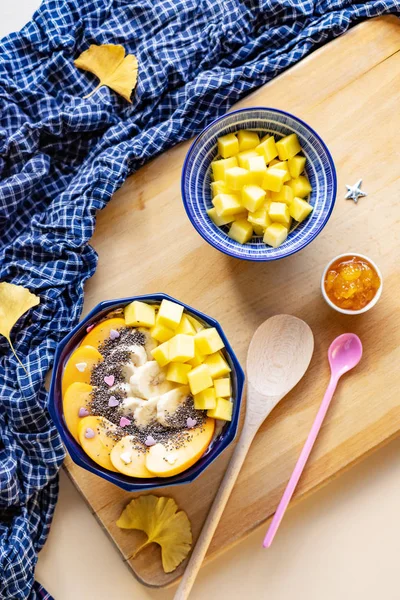 Breakfast bowl with oat, yogurt, mango, persimmon and chia, top view