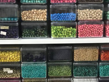 Çok renkli boncuklarla dolu saydam dikdörtgen plastik kaplar.