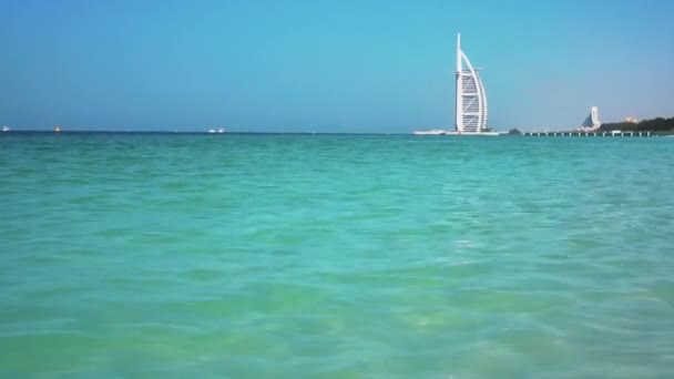 DUBAI, Emiratos Árabes Unidos - 20 de enero de 2018. Burj al Arab Hotel en el fondo. Olas en la playa de Al Sufouh. Mar. Golfo Pérsico . — Vídeo de stock