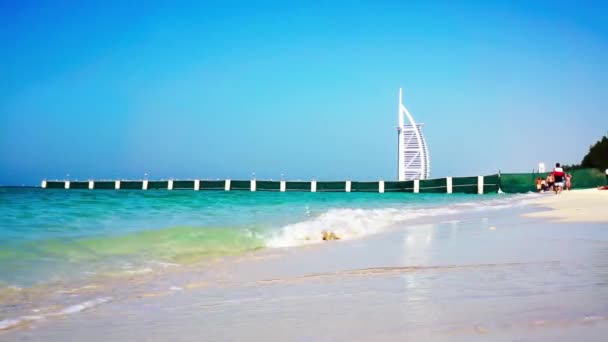 DUBAI, Emiratos Árabes Unidos - 20 de enero de 2018. Burj al Arab Hotel en el fondo. Olas en la playa de Al Sufouh. Mar. Golfo Pérsico . — Vídeos de Stock